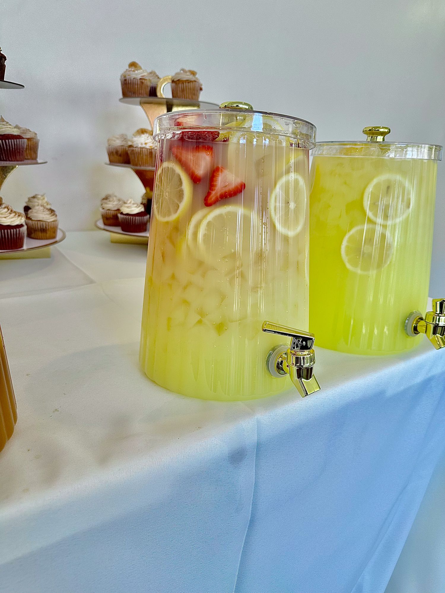 Row of clear drink dispensers containing yellow and citrus-infused beverages for serving.