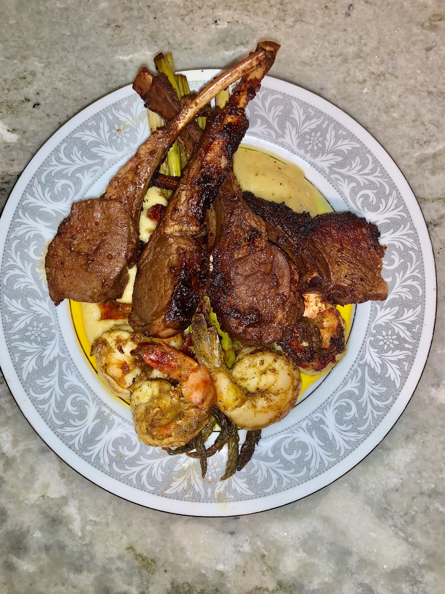Grilled meat and vegetables plated elegantly on decorative white dishes.