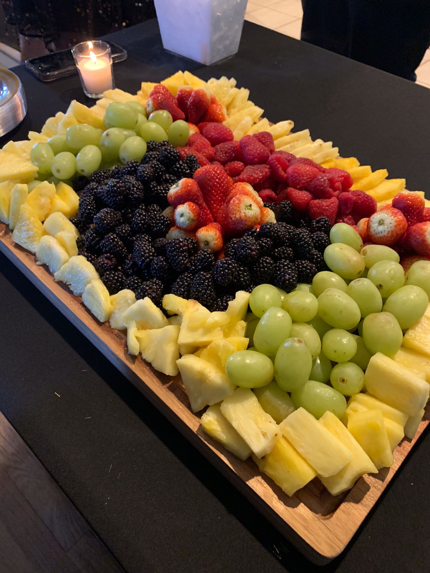 Fresh fruit and cheese platter with grapes, berries and cubed cheese on a wooden board.
