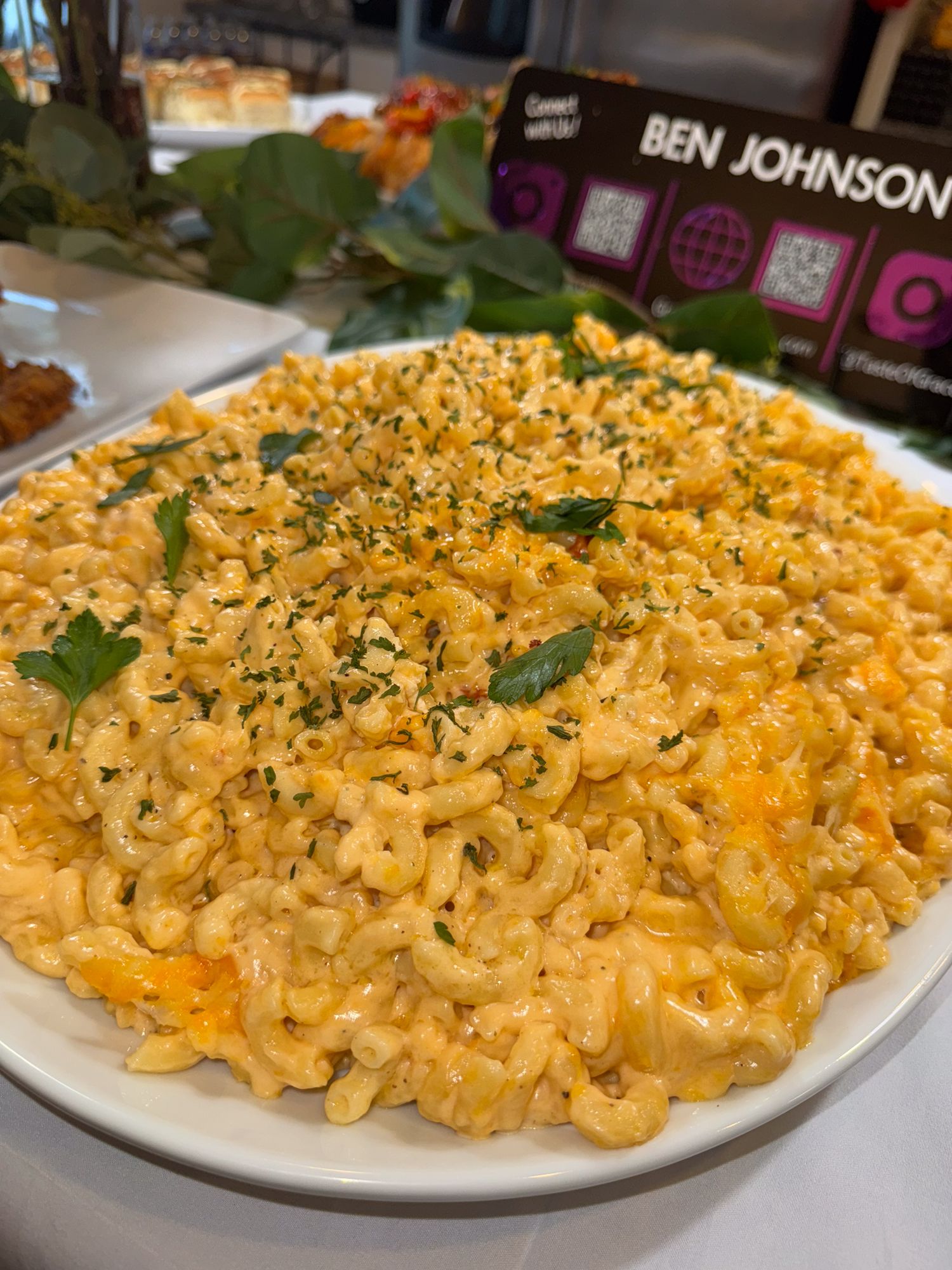 Creamy mac and cheese topped with herbs and breadcrumbs served on a white plate.