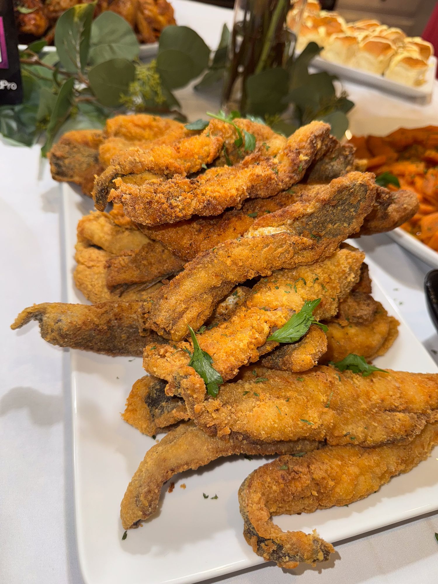 Crispy fried chicken wings garnished with fresh herbs served on a white platter.
