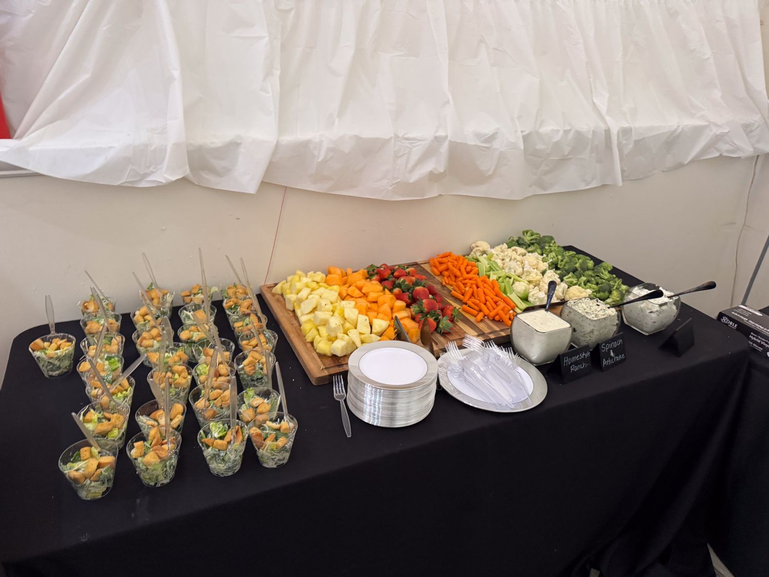 A long buffet table displays various appetizers and snacks arranged on black serving platters.