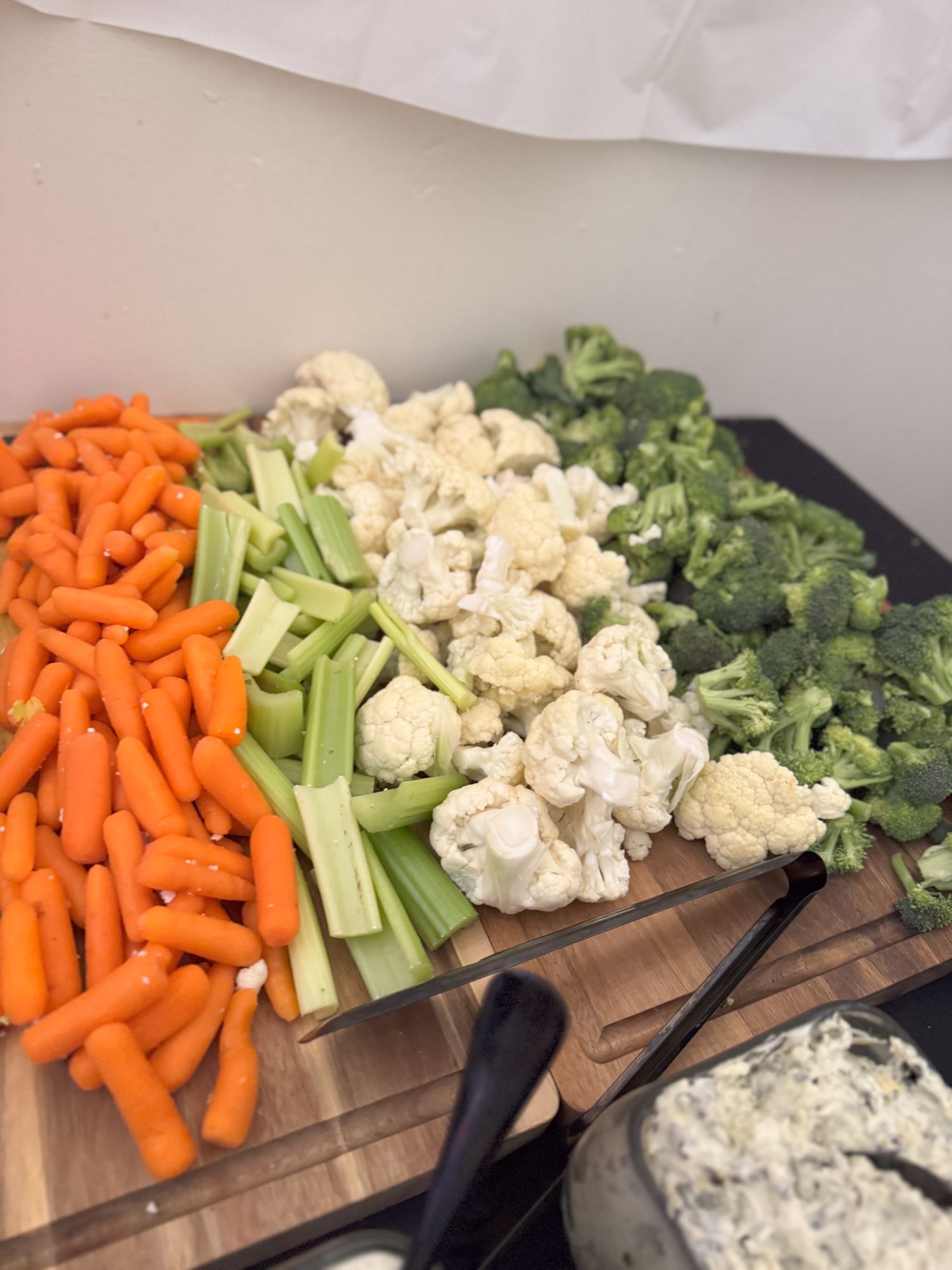 Fresh cut vegetables including carrots, celery, cauliflower and broccoli arranged on wooden cutting boards.
