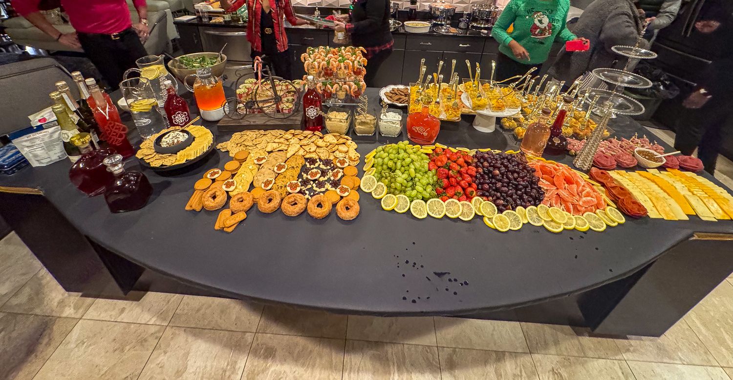 Colorful party buffet spread with fresh fruit, cheese, crackers and appetizers on a curved table.