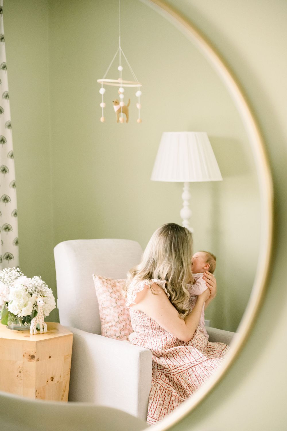 A series of mirror reflections show someone sitting in a white chair against a sage green wall with hanging pendant lights.