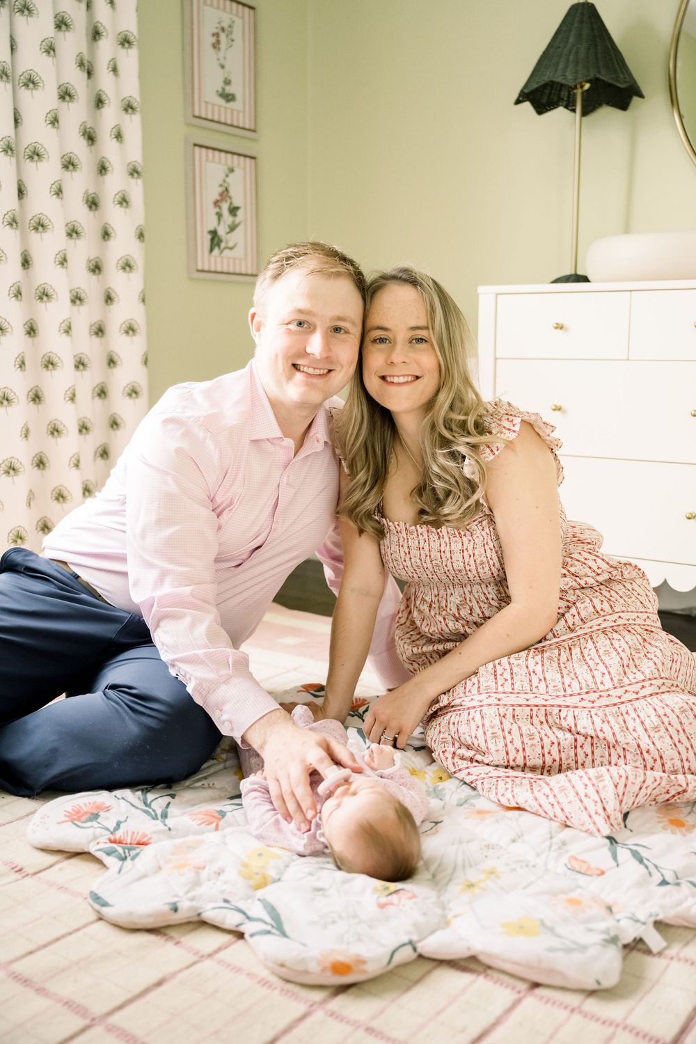 A couple in coordinated pink and white outfits lounges together on a floral patterned bed.