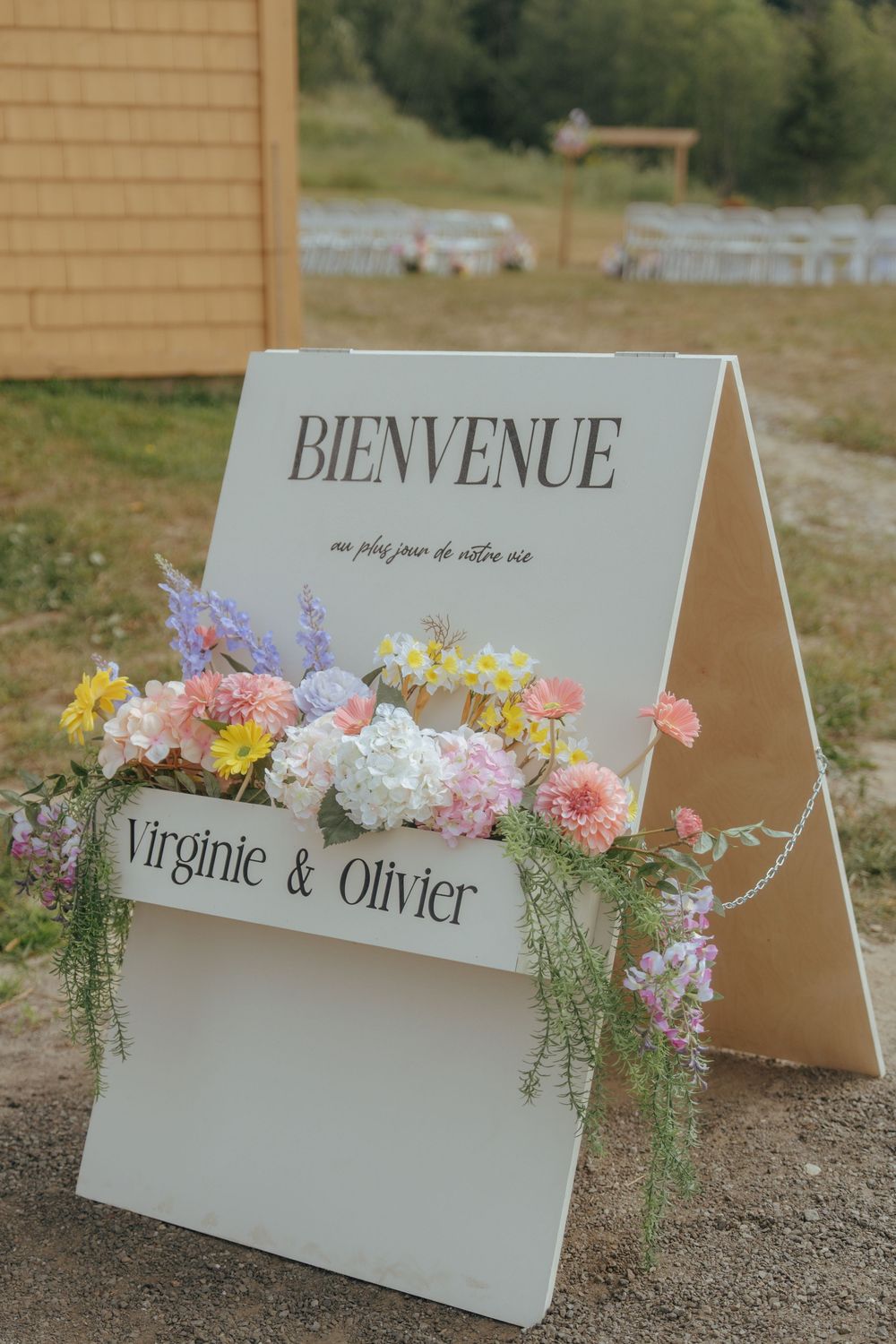Decorative wedding welcome signs with floral arrangements displayed outdoors on natural terrain.