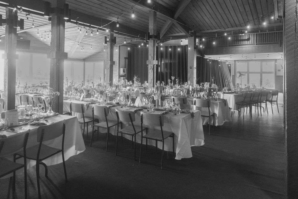Large indoor reception venue with string lights and tables set up for a wedding celebration.