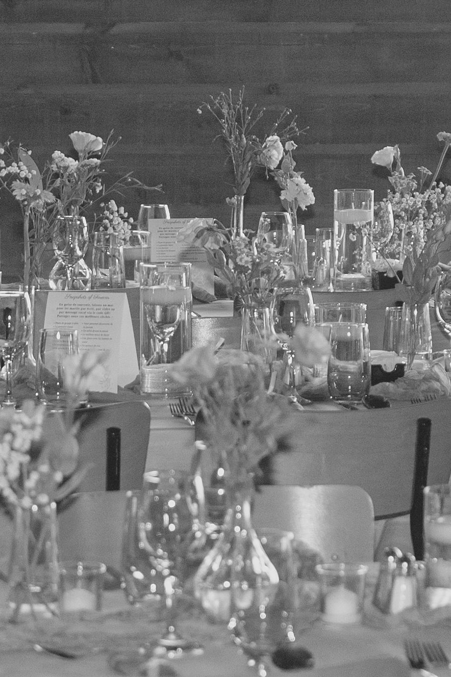 Elegant black and white table setting with delicate floral centerpieces in glass vases and candlelight for a formal event.
