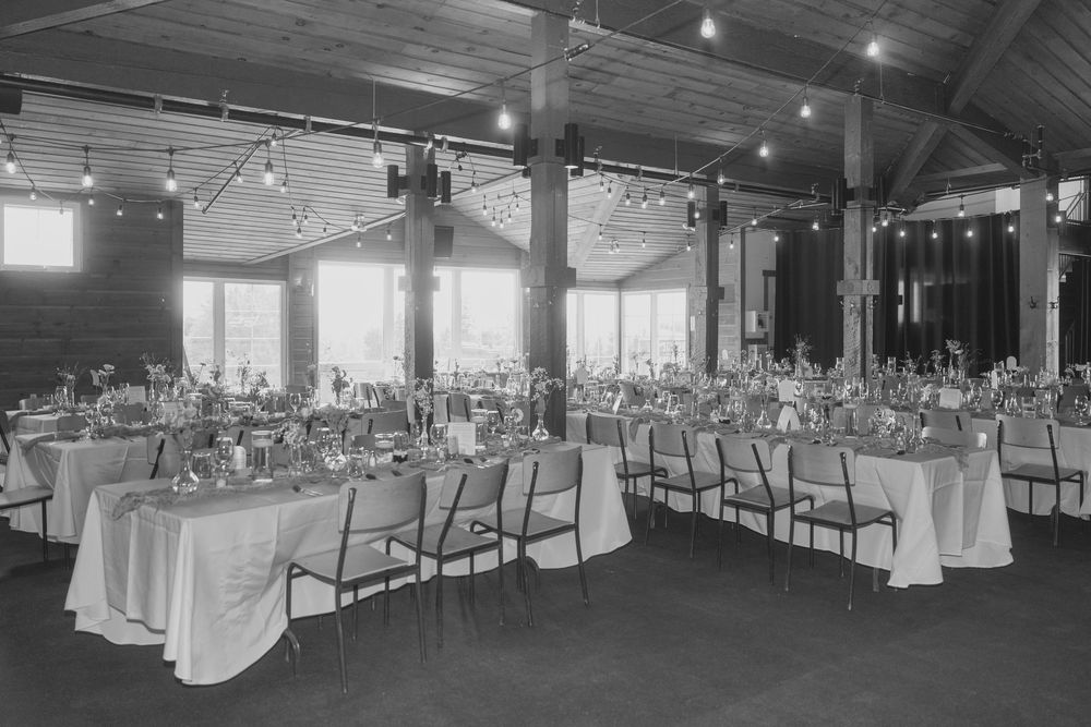 Large indoor wedding reception venue with elegant table settings and string lighting.