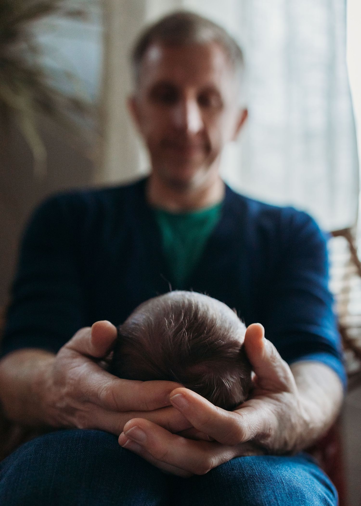 A series of photos showing a sleeping baby being gently cradled in someone's hands against a soft white background.