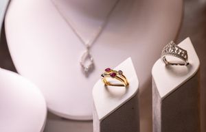 Elegant gold and silver jewelry pieces including rings and necklaces displayed on white ceramic holders.