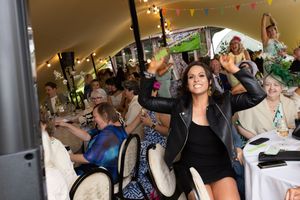 Guests celebrate at a lively indoor party with colorful bunting decorations and tables set for dining.