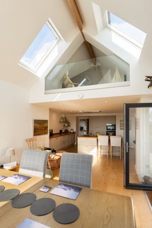 Modern loft apartment with skylights, hardwood floors, and round gray seating cushions arranged in an open floor plan.