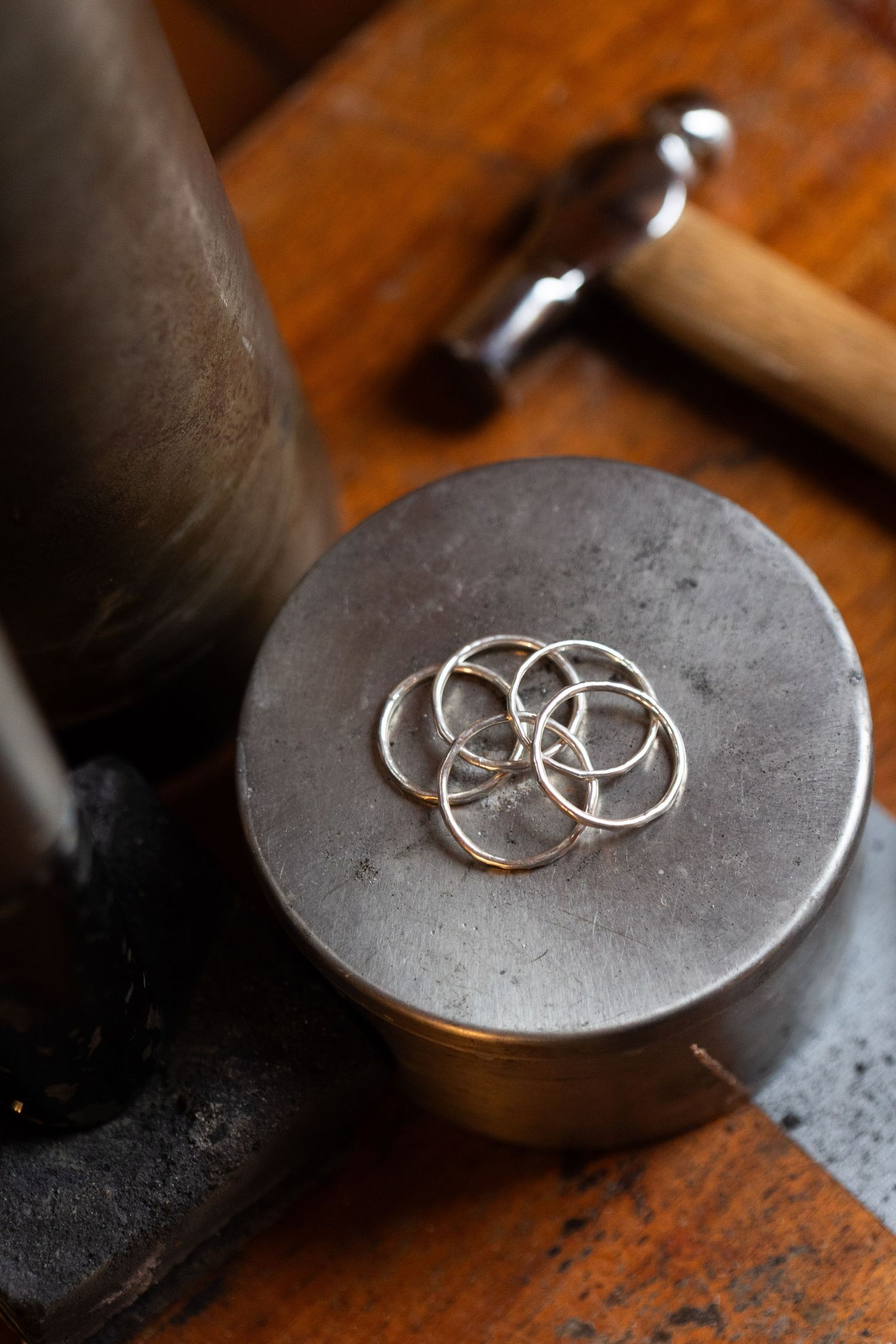 Silver wedding rings photographed in detail on a dark textured metal surface.
