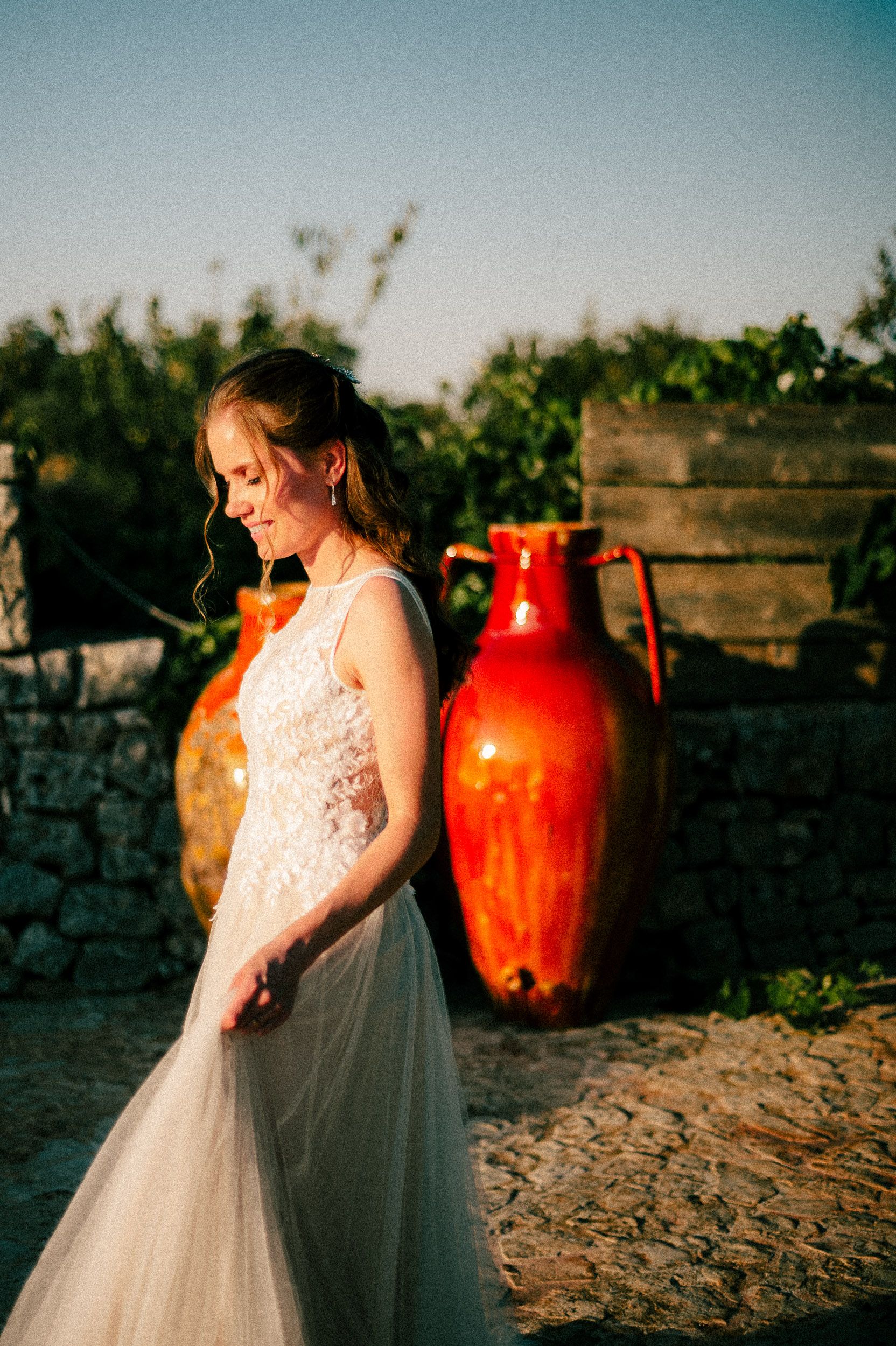 A romantic wedding scene at sunset with red ceramic vases in the background creating a warm Mediterranean atmosphere.