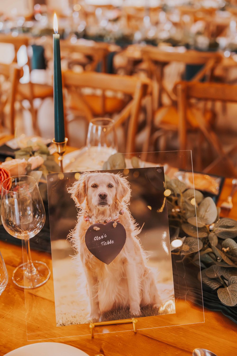 Wedding table setting with rustic decor featuring a golden retriever photo display and eucalyptus leaves.