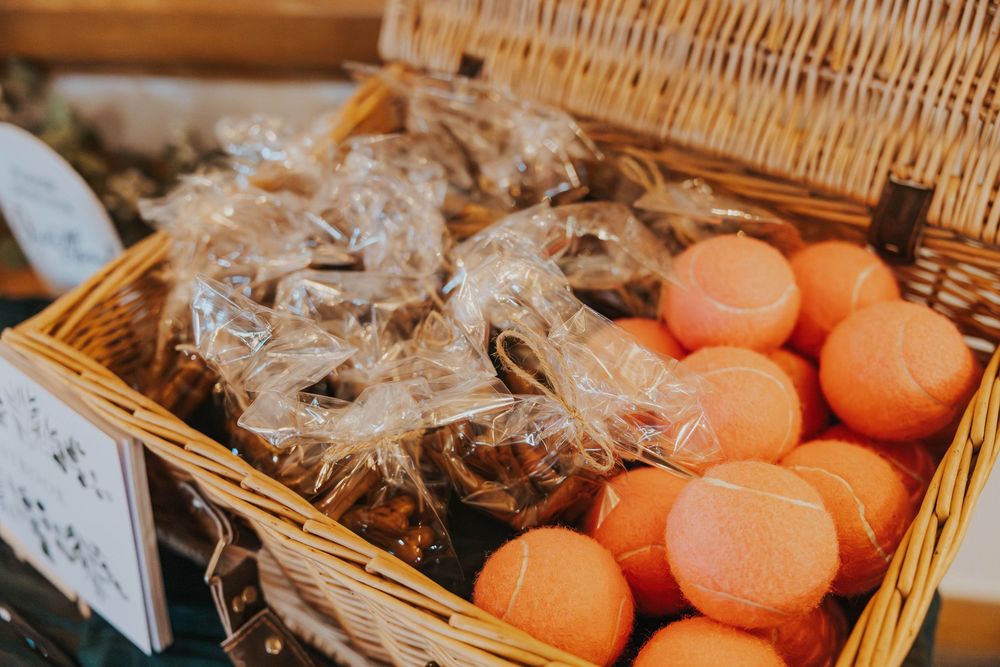 Fresh oranges and wrapped baked goods displayed in a woven basket at a market or bakery.