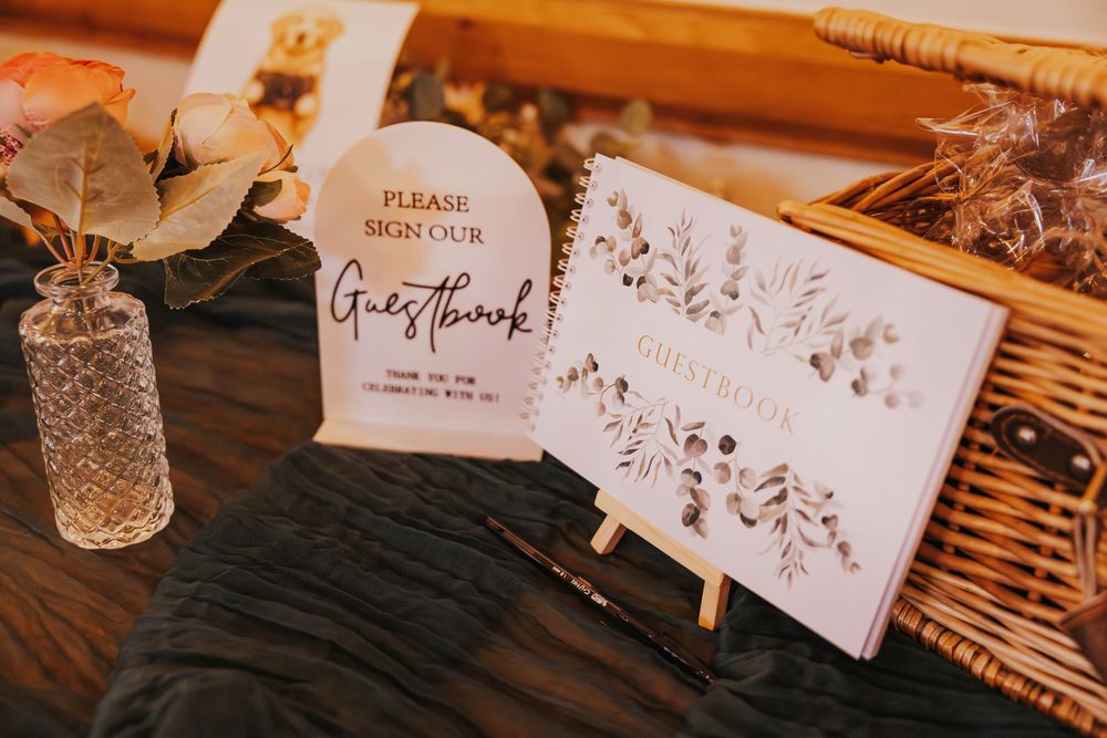 Place cards with elegant calligraphy sit on a rustic wooden surface beside delicate floral arrangements and glassware.