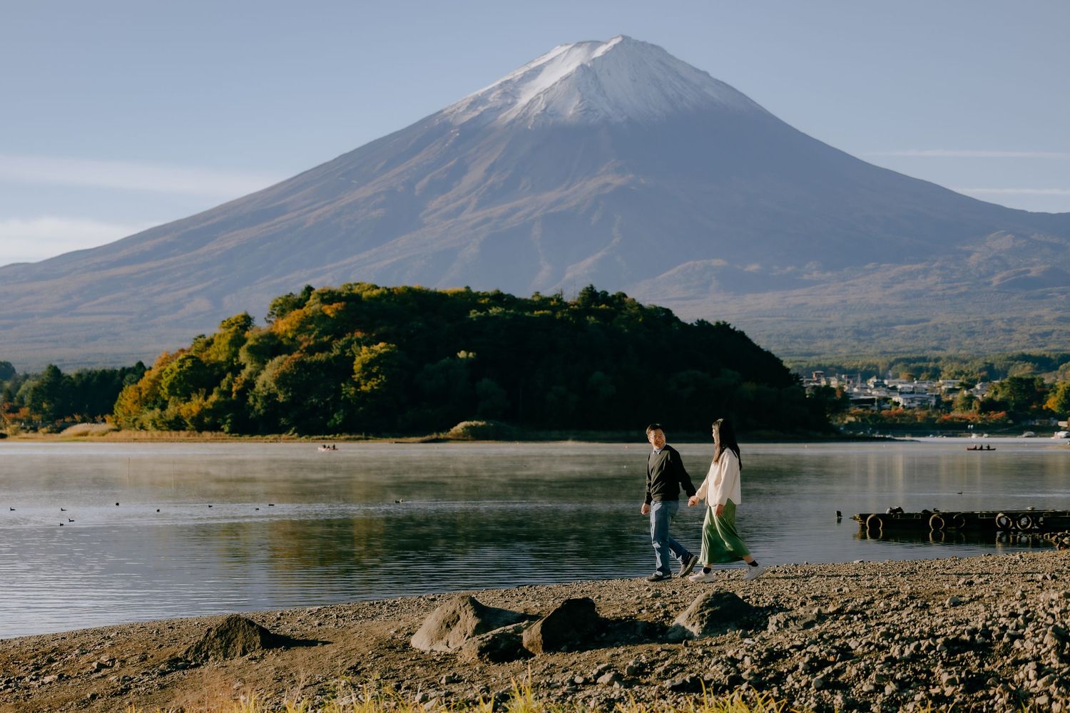 Mount Fuji rises majestically above Lake Kawaguchiko in Japan during a clear autumn day with golden foliage.