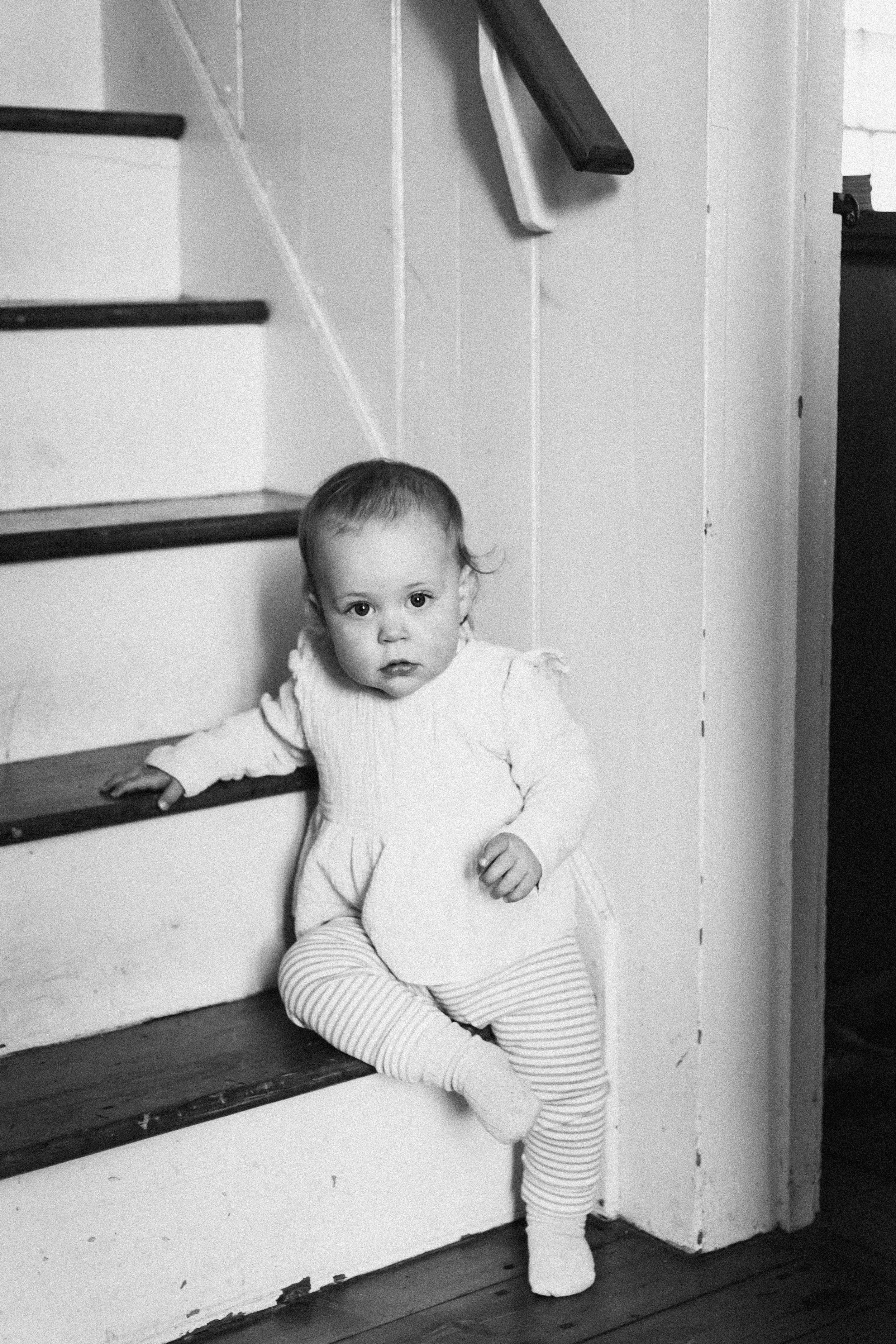 A series of black and white photos showing a baby peeking around a white doorway or corner.