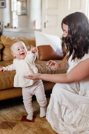 A sequence of photos showing a baby learning to walk while holding onto a white lace dress for support.