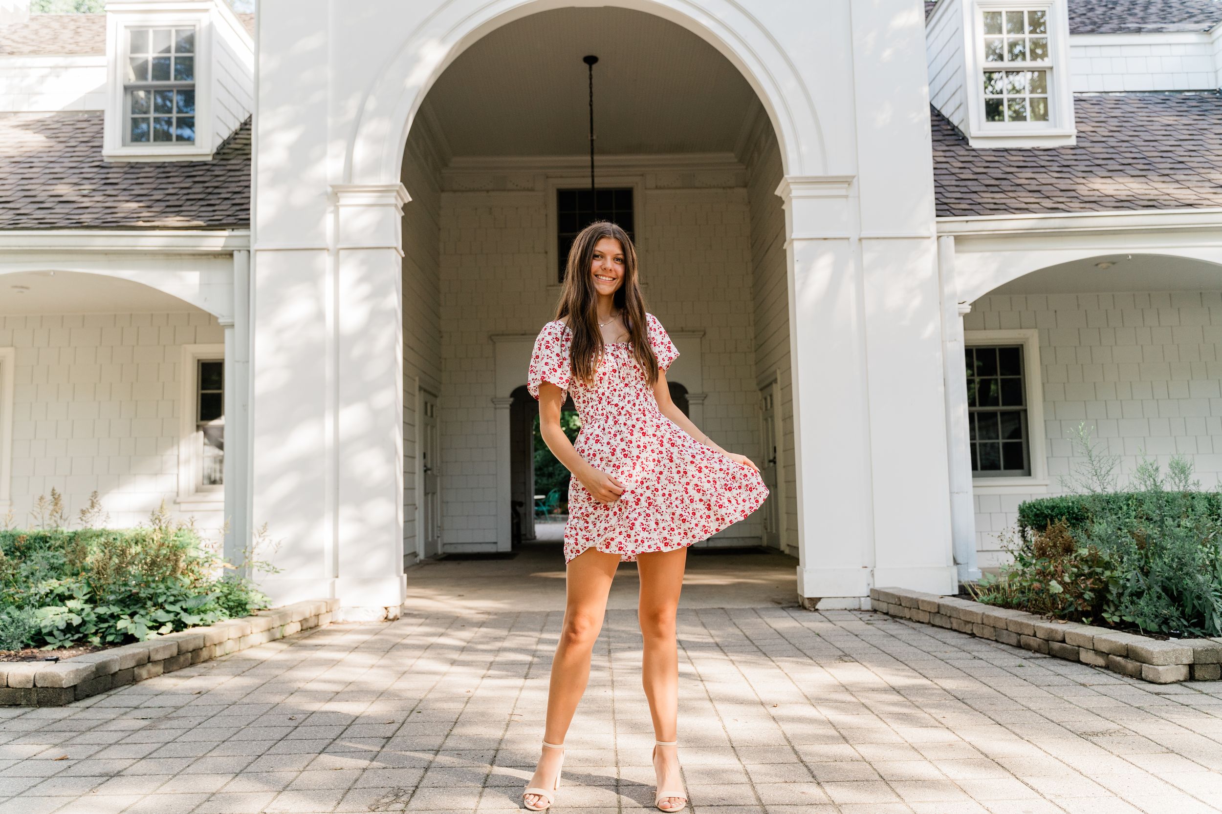 A series of photos showing a pink floral dress being twirled in an elegant white archway courtyard setting.