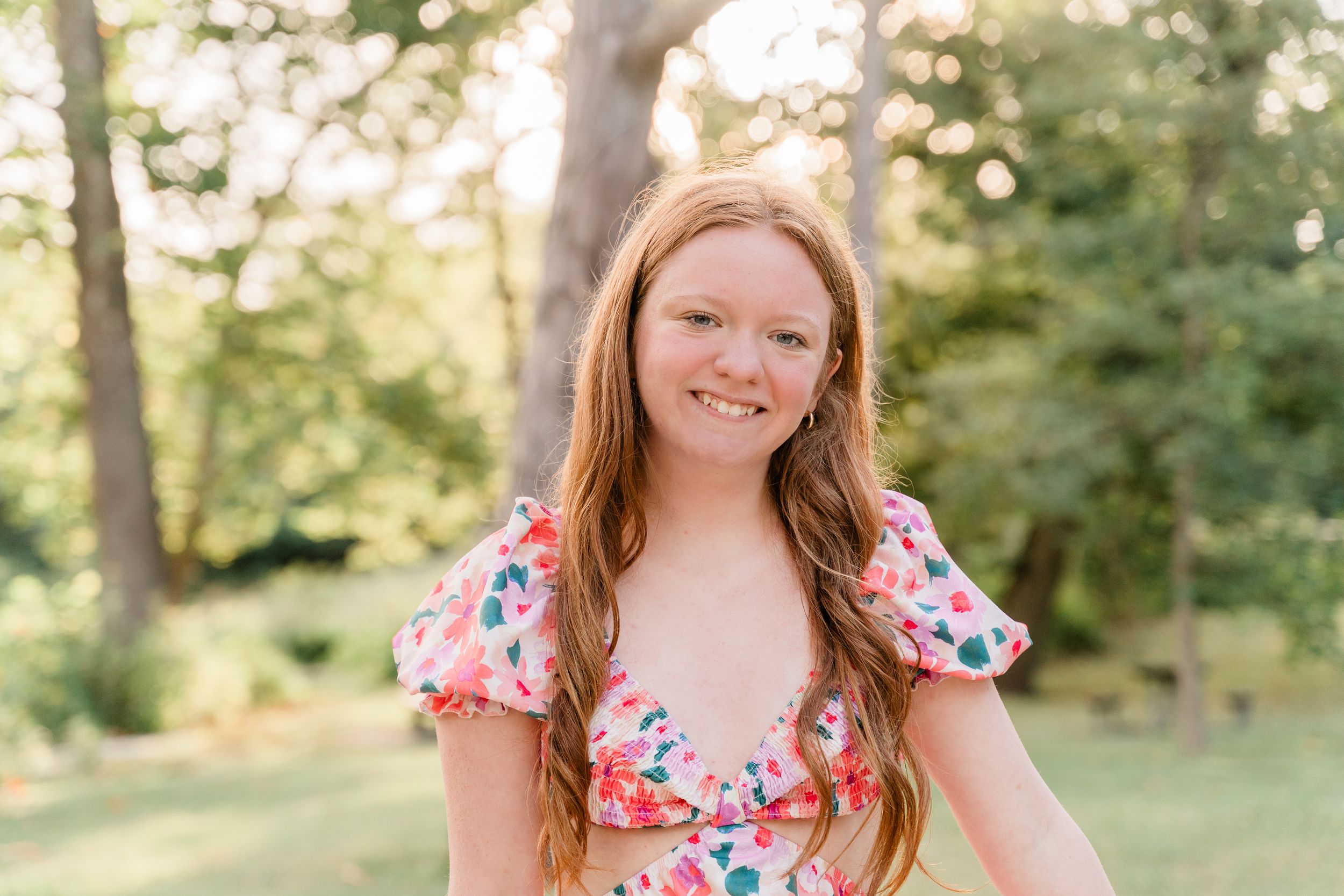 A floral dress photoshoot in a sunny park with natural bokeh lighting effects.