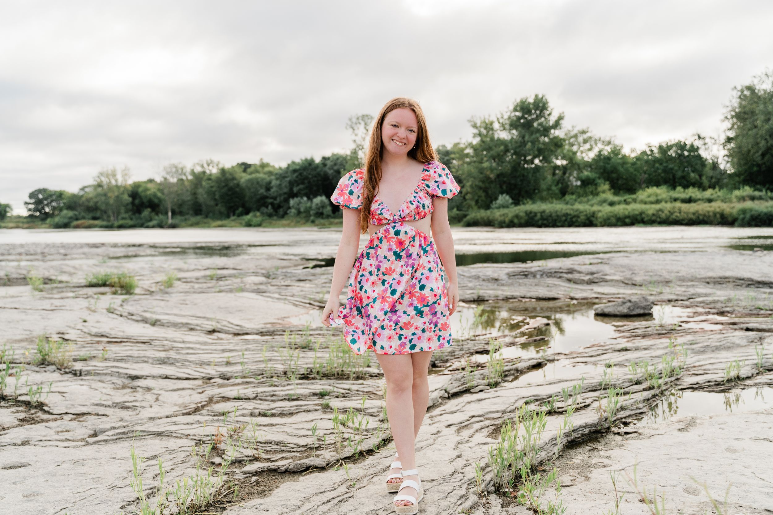 A summer portrait session on rocky terrain near a peaceful waterfront landscape.
