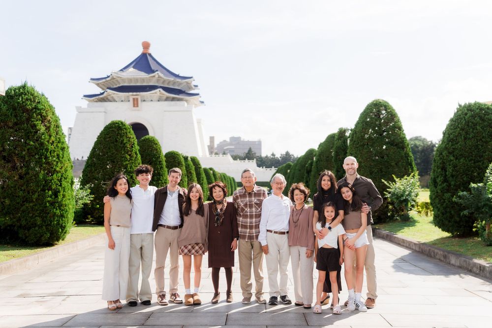 Wedding party members lined up under a white gazebo in formal attire on a bright sunny day.