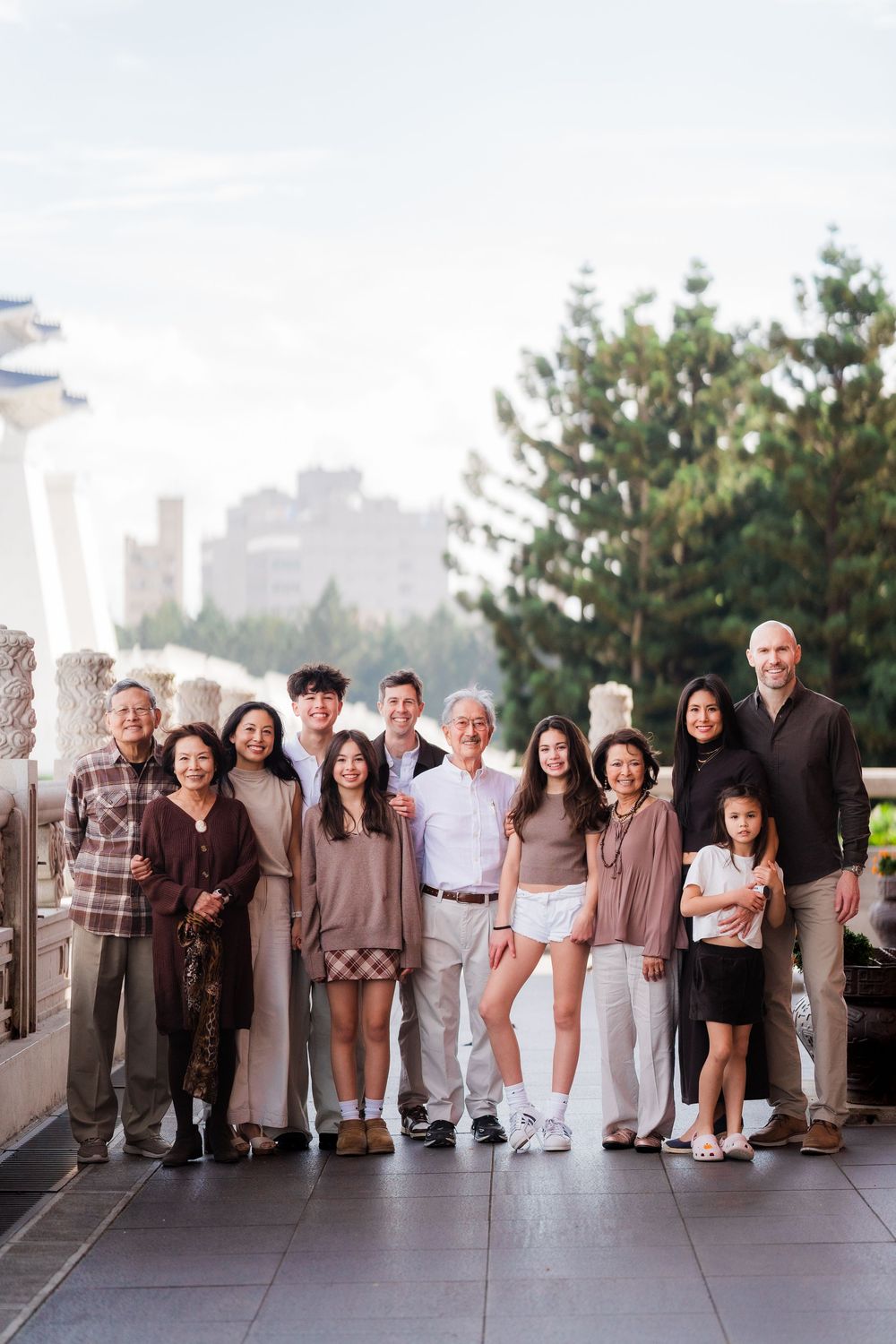 A large multi-generational group poses together on an outdoor observation deck with city views in the background.