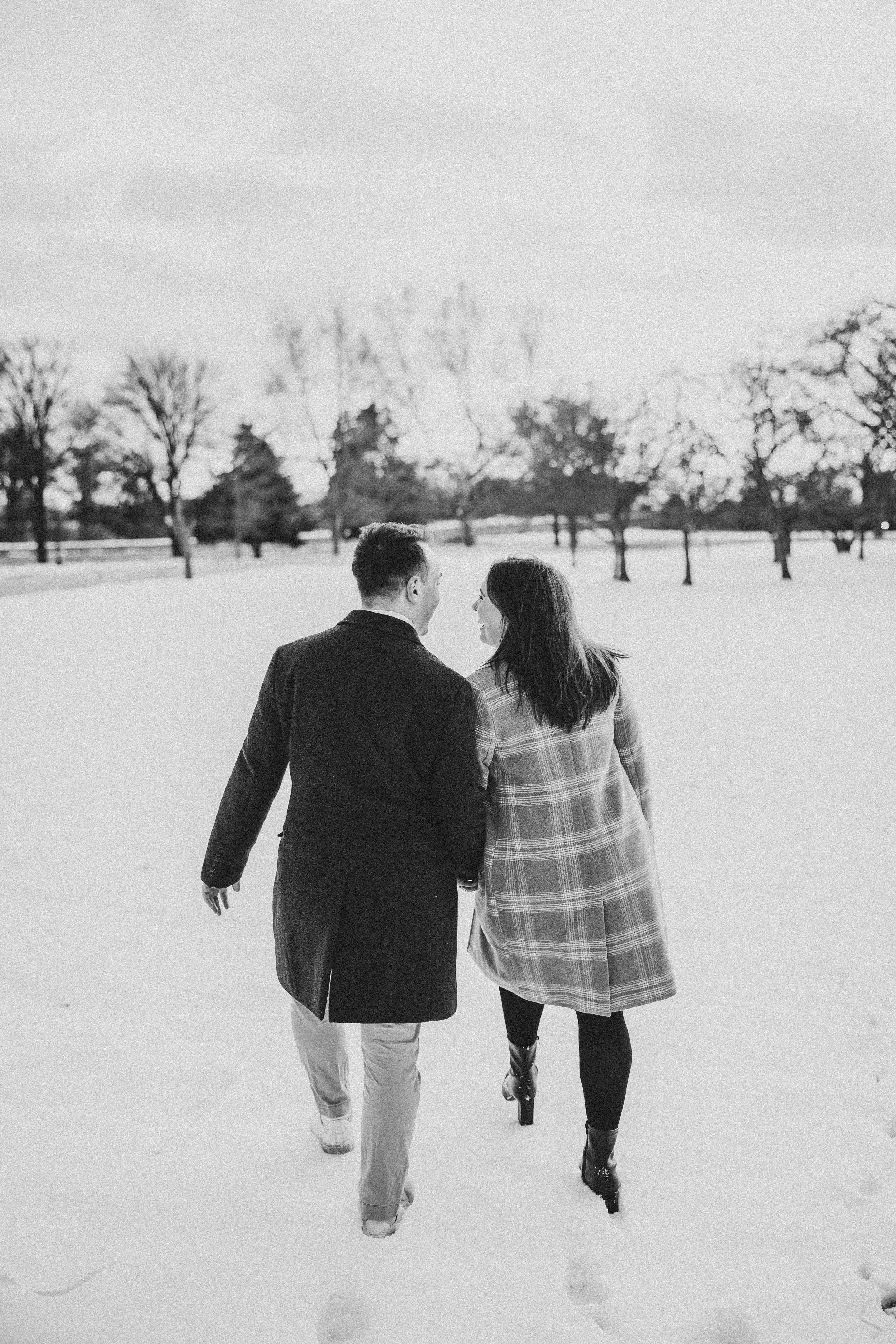 A couple walks through a snowy passage in black and white photography at a great dc winter proposal location, the jefferson memorial