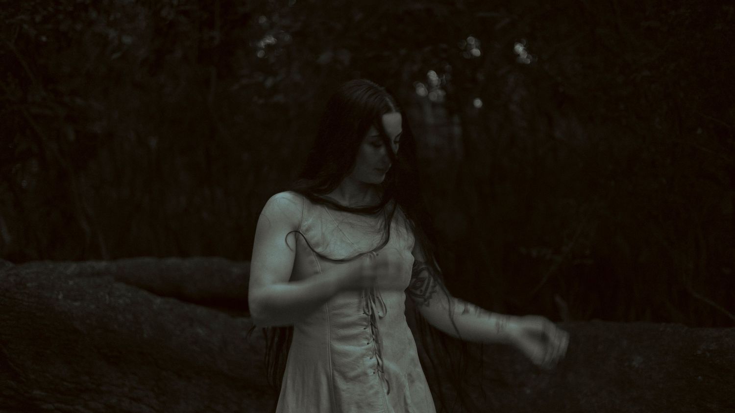 A dark and moody series of six black and white photographs showing a woman in a dress against a shadowy background.