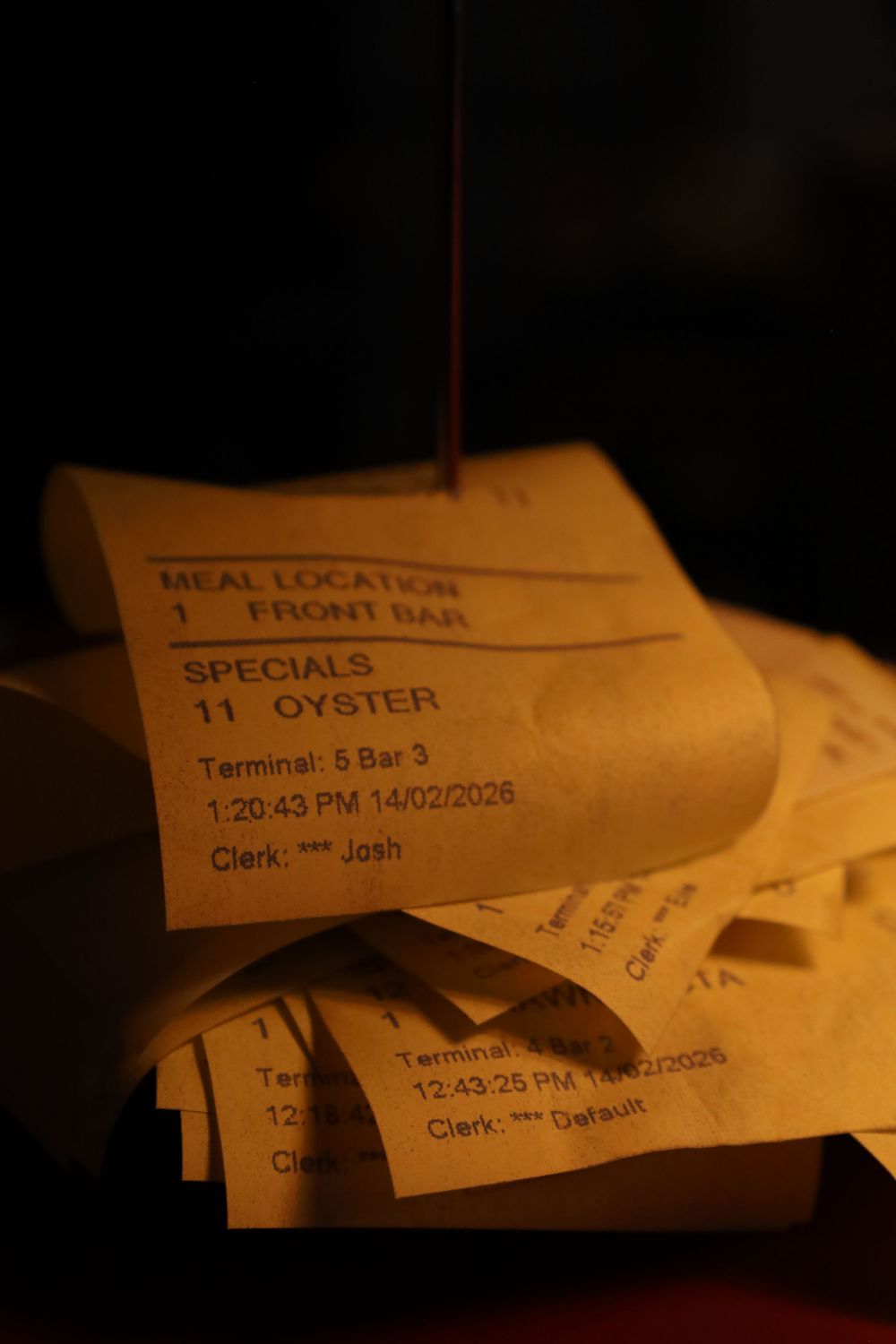 Close-up of restaurant order tickets stacked on a dark surface with 'SPECIAL' and 'OYSTER' text visible.