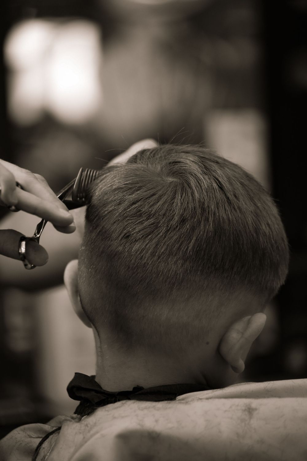 A black and white photo series showing a person getting a haircut at a barber shop with clippers.