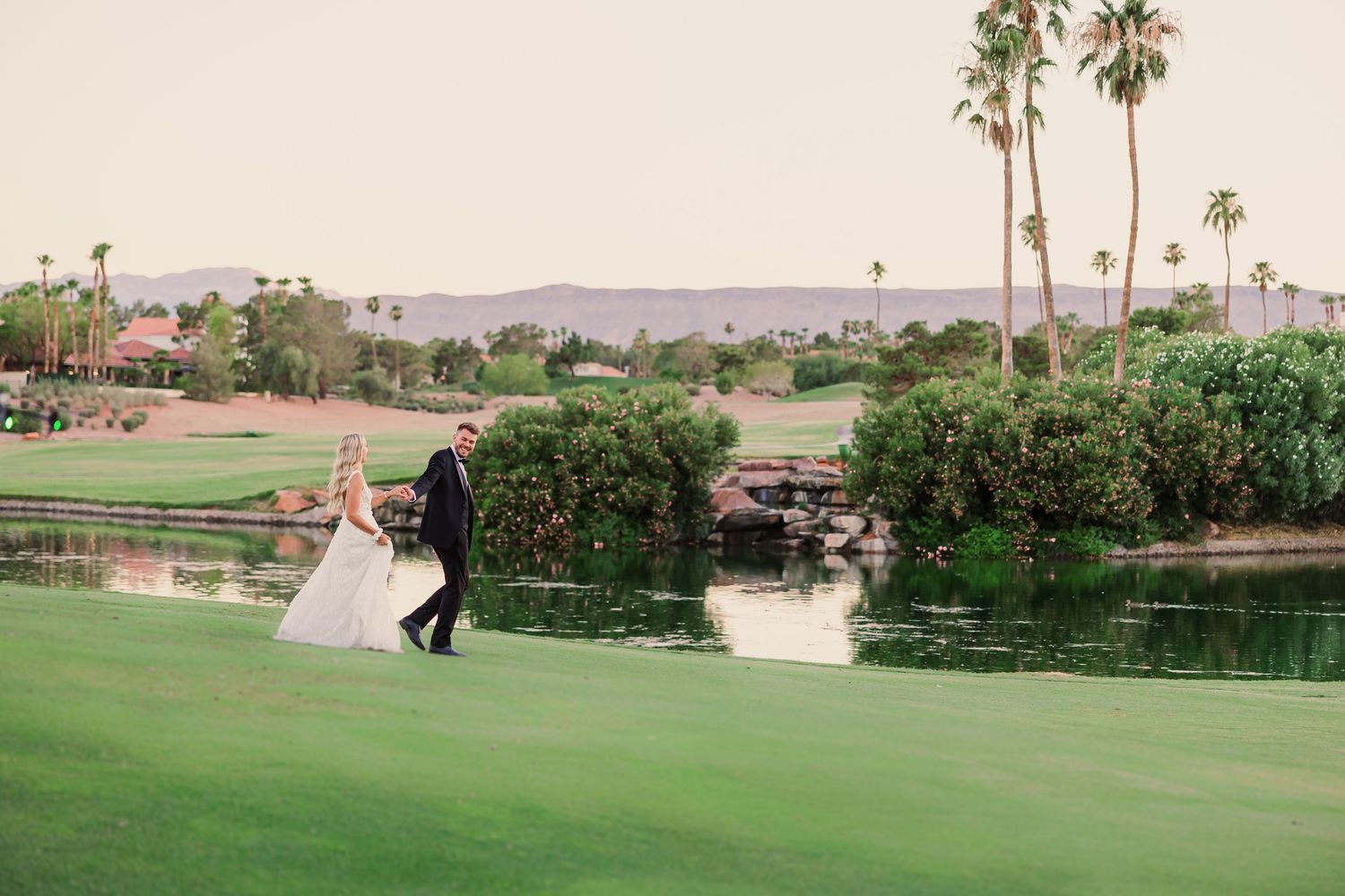 A scenic desert golf course with palm trees, lush greens, and mountains in the background.