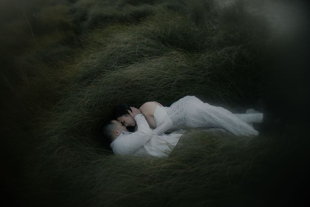 A series of dark moody photographs showing a woman in a white dress lying on grass in different poses.