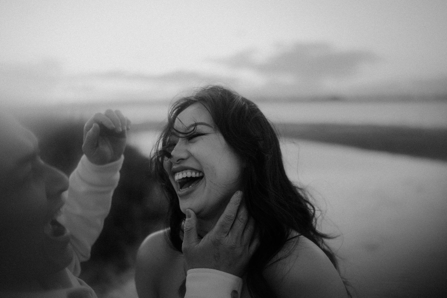 A series of black and white photos showing a couple embracing and sharing intimate moments at sunset.