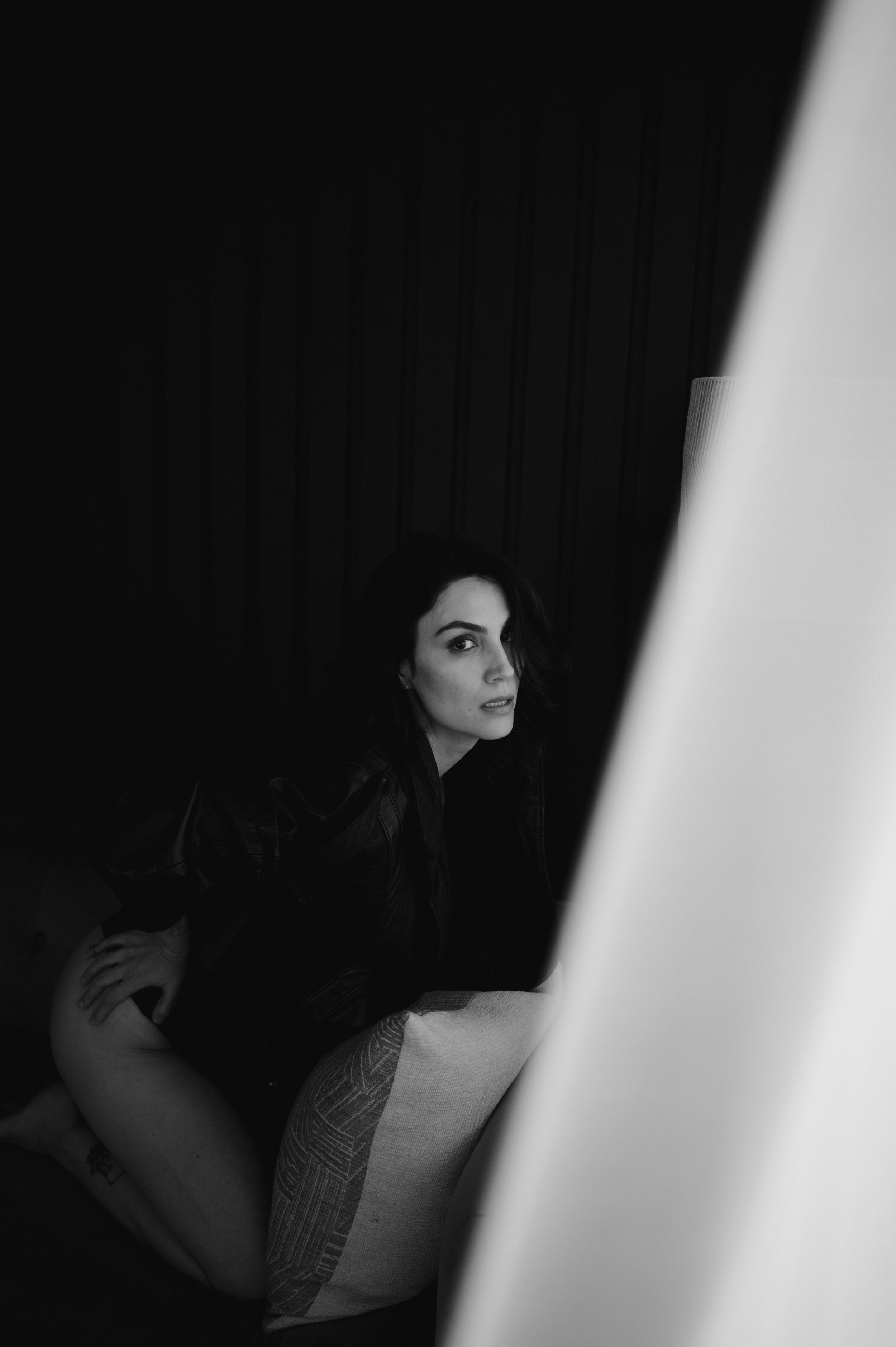 Artistic black and white portrait of a person in shadow against a dark background.