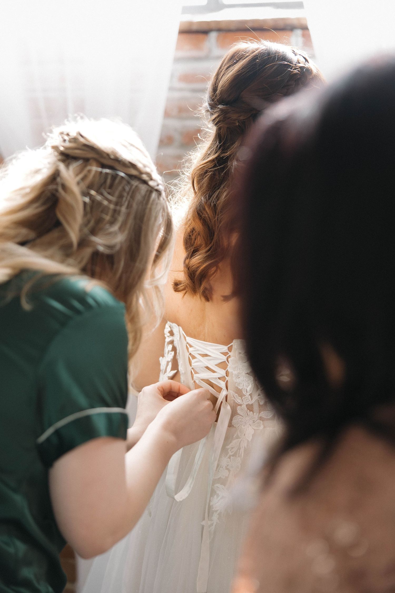 Close-up view of white lace corset detailing on a wedding dress being fastened.