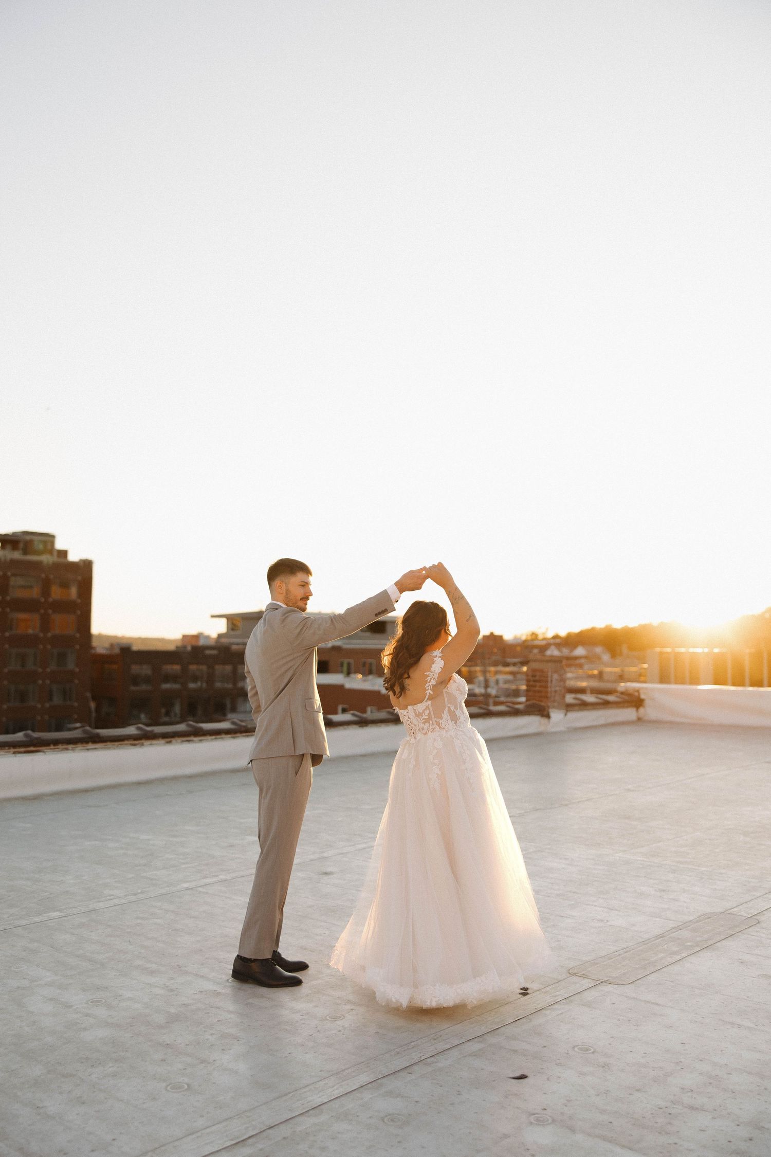 Couple dancing together on a rooftop at sunset with golden light illuminating their silhouettes.