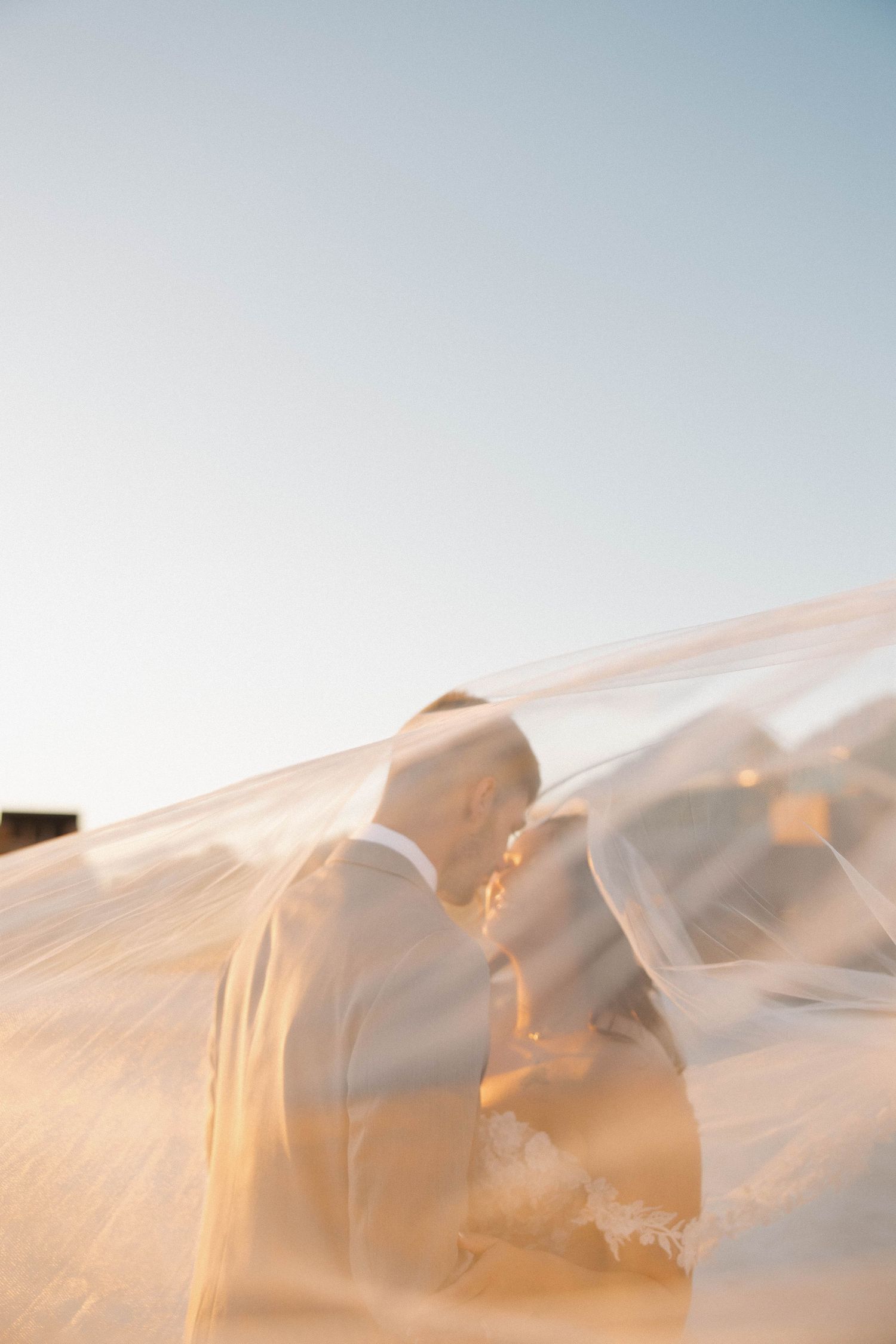 Ethereal white fabric billows softly against a pale blue sky during golden hour creating a dreamy atmosphere.