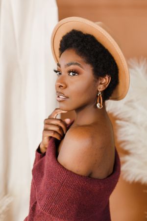 A portrait series showing different poses in a burgundy off-shoulder sweater and beige beret against a warm background.