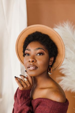A fashion portrait series showing a person in a burgundy sweater and tan hat against a white background.
