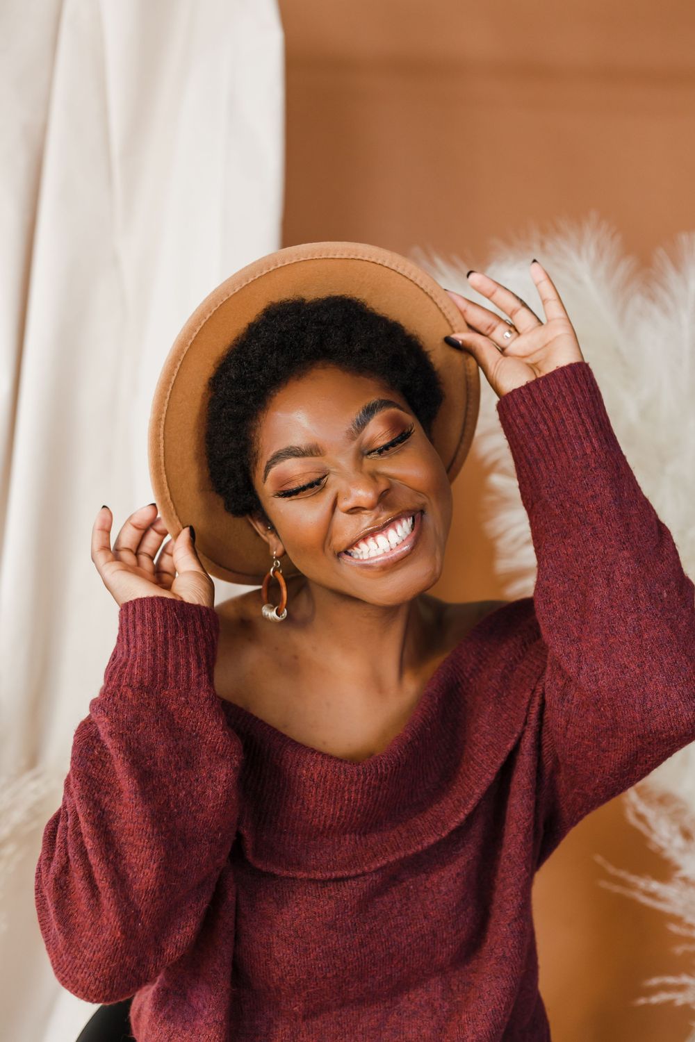 A person in a burgundy turtleneck sweater smiles joyfully while posing in a sequence of expressive shots.