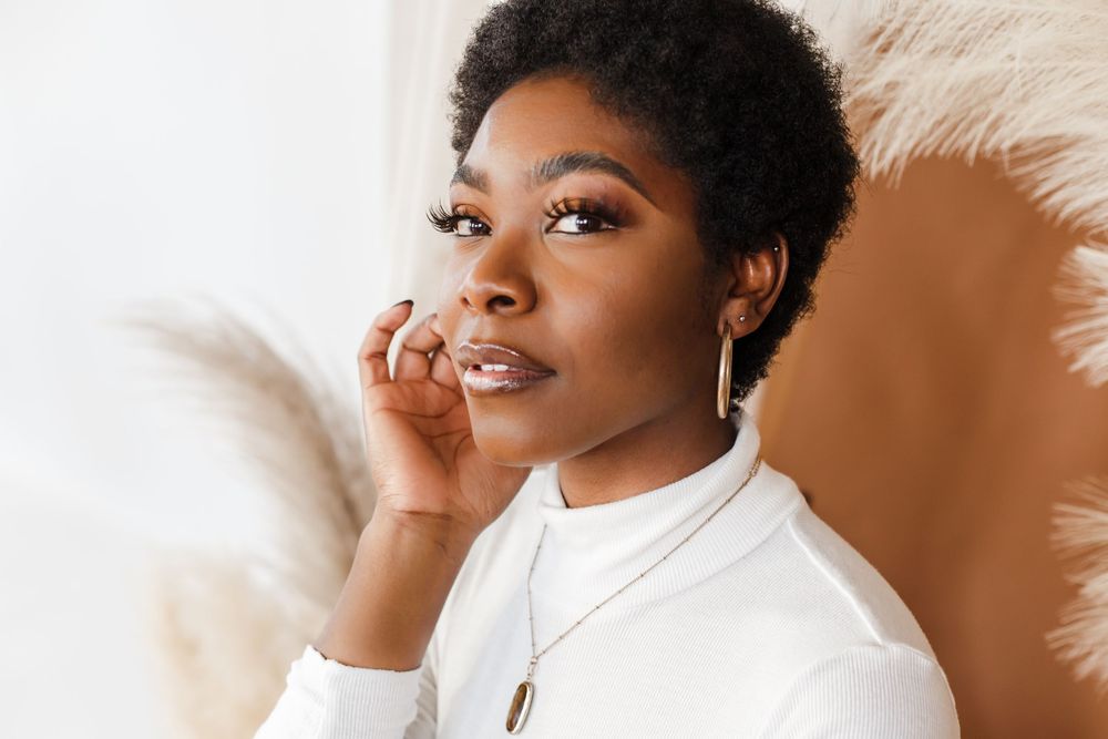 Professional beauty portrait with warm lighting against a neutral background showcasing natural makeup and glowing skin.