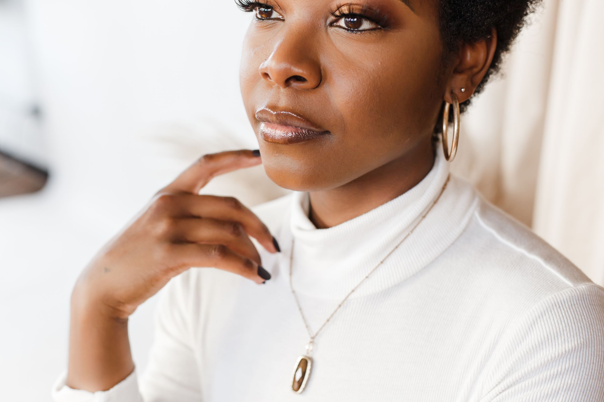 A series of four headshots showing someone wearing a white turtleneck sweater against a light background.