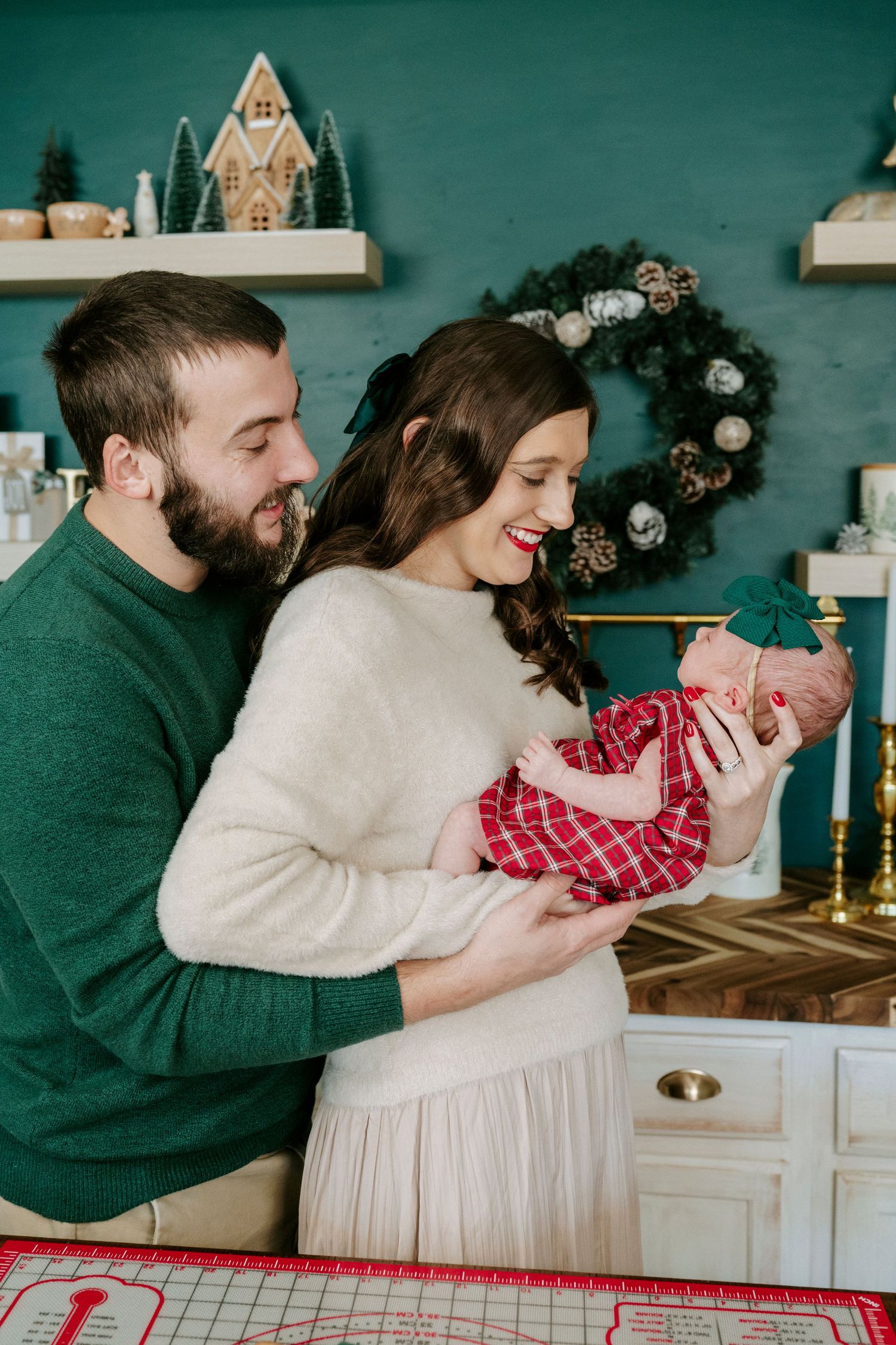 Couple laughing together in cozy holiday setting with teal wall and festive decor.