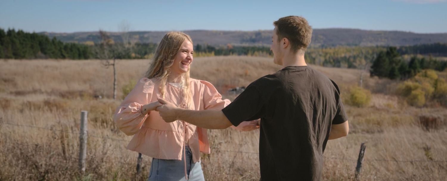 Two people holding hands in conversation against desert mountain backdrop.