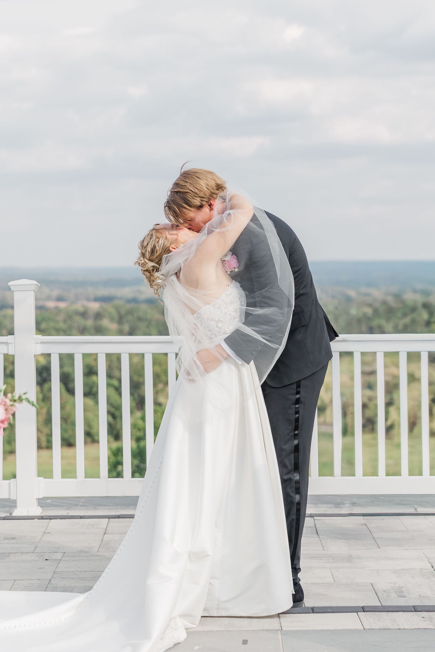 Intimate wedding ceremony exchange on a white terrace overlooking a scenic mountain landscape.